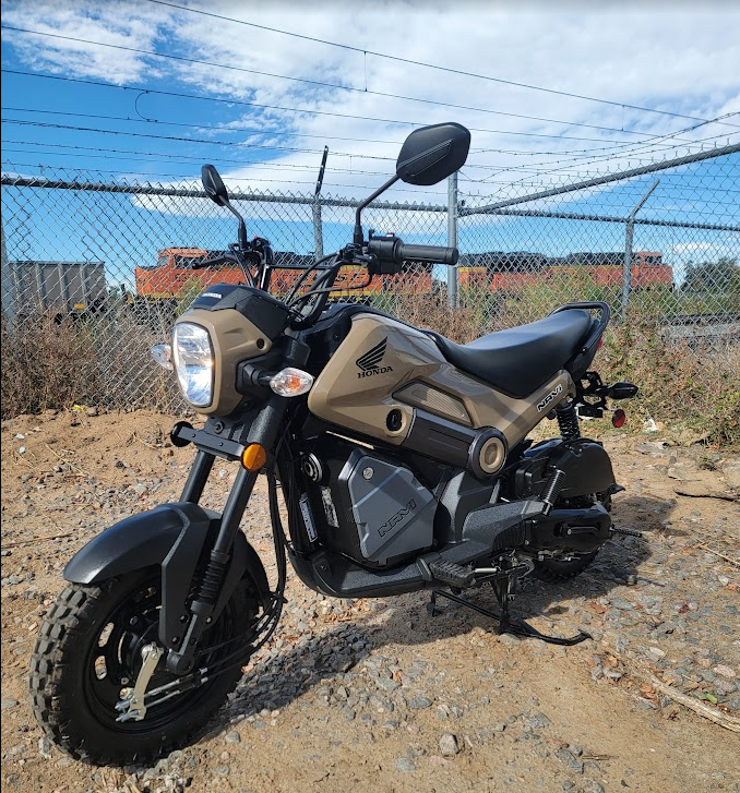2023 Honda Navi, chain-link fence backdrop