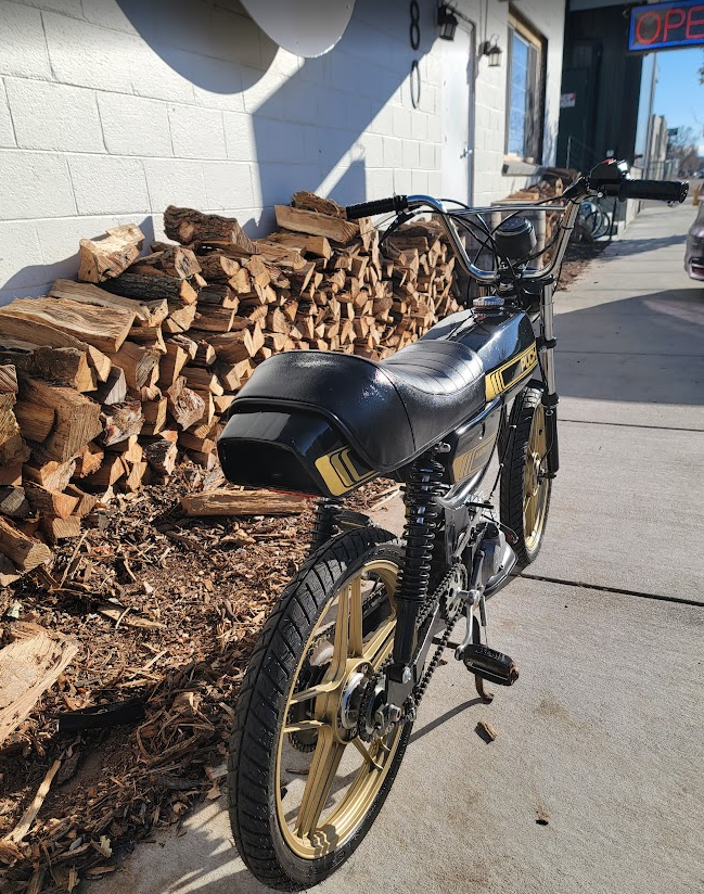 1980 Puch Magnum black and gold, rear wheel by woodpile